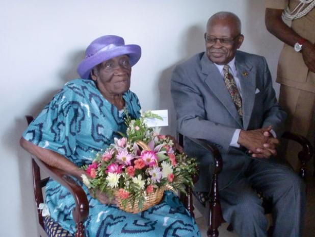 The island’s latest centenarian Myrtle Lucas admiring the flowers presented to her by His Excellency Sir Elliott Belgrave, Governor General of Barbados.