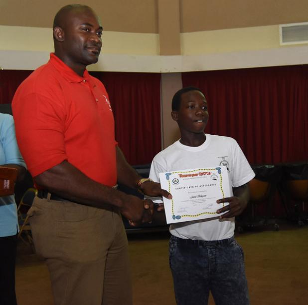  Jared Belgrave (right) receives his certificate of attendance at the closing ceremony for the Juvenile Liaison Scheme’s Summer Camp Programme.