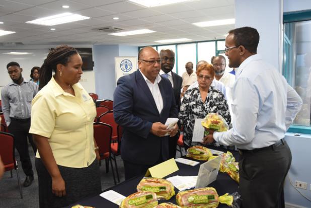 Purity Bakeries’ Sales and Distribution Manager, Christopher Symmonds (right), tells Vermaran Extavour, Regional Cassava Development Coordinator with the Food and Agriculture Organisation (left) and Minister of Agriculture, Food, Fisheries and Water Resource Management, Dr. David Estwick, about the new cassava blended bread.  