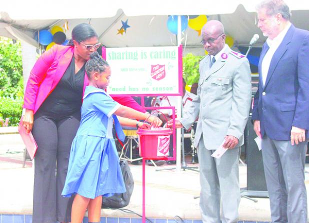 Scotiabank Junior Calypso Monarch Summa ‘Summa’ Sargeant makes the first official donation under the watchful eye of Scotiabank Director of Finance Colleen Cyrus (left), while Salvation Army Divisional Commander Major Sinous Theodore; and Chairman of the Salvation Army’s Advisory Board, Paul Bernstein look on. 