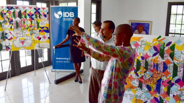Barbadian contemporary artist, Sheena Rose, recently presented new artwork to the IDB Barbados Country Office. Here she is pictured explaining the significance of the paintings to IDB staff member, Vinicio Rodriguez.