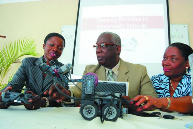 (from left) Erdiston Teachers’ Training College Senior Tutor and Science Teacher, Dr. Ramona Archer-Bradshaw, shows Minister of Education, Science, Technology and Innovation, Ronald Jones, and Principal Barbara Parris, how to operate the VEX Robot.  