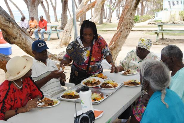 (Standing) Home Care Supervisor, Pamela Perry, assisting some of the individuals at the picnic with their meals.