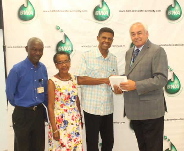(right to left) Representative of Cowater International Inc., David McCartney, presents Hallam Collins with his brand new iPad Mini 4 yesterday, while his wife, Yvette Collins and Barbados Water Authority General Manager, John Mwansa, look on.