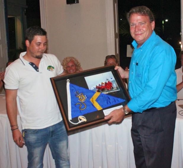 Clipper Round the World Alumnus, Michael Jones, handing over a photo of the Visit Seattle crew to Barbados Yacht Club Commodore Geoffrey Evelyn.