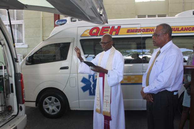Canon Noel Burke blessing the two new ambulances presented to the Department of Emergency Ambulance Services on yesterday, as John Boyce looks on.