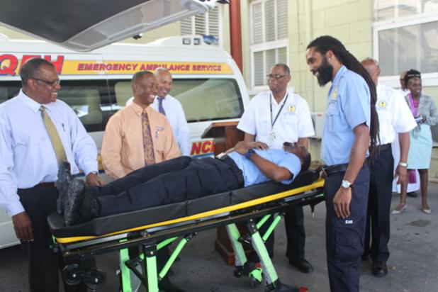 Emergency Medical Technician, Anderson Nurse, testing out one of the new stretchers. Included in those looking on are Health Minister, John Boyce, Head of the Department of Emergency Ambulance Services, Dr. David Byer (third from left) and NASSCO Sales Director, Roger Moore (second from left).