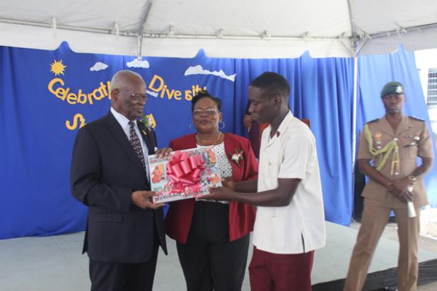 Head Boy of the Irving Wilson School, Shaquone Hoyte, presenting a gift on behalf of the school to Government General of Barbados, His Excellency Sir Elliott Belgrave. Looking on is Principal of the school, Wendy Blackman.