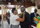 Sister Monette Collymore pins a boutonnière on Prime Minister Freundel Stuart as he arrived at the Bethesda Tabernacle for the DLP’s 62nd anniversary service yesterday morning.